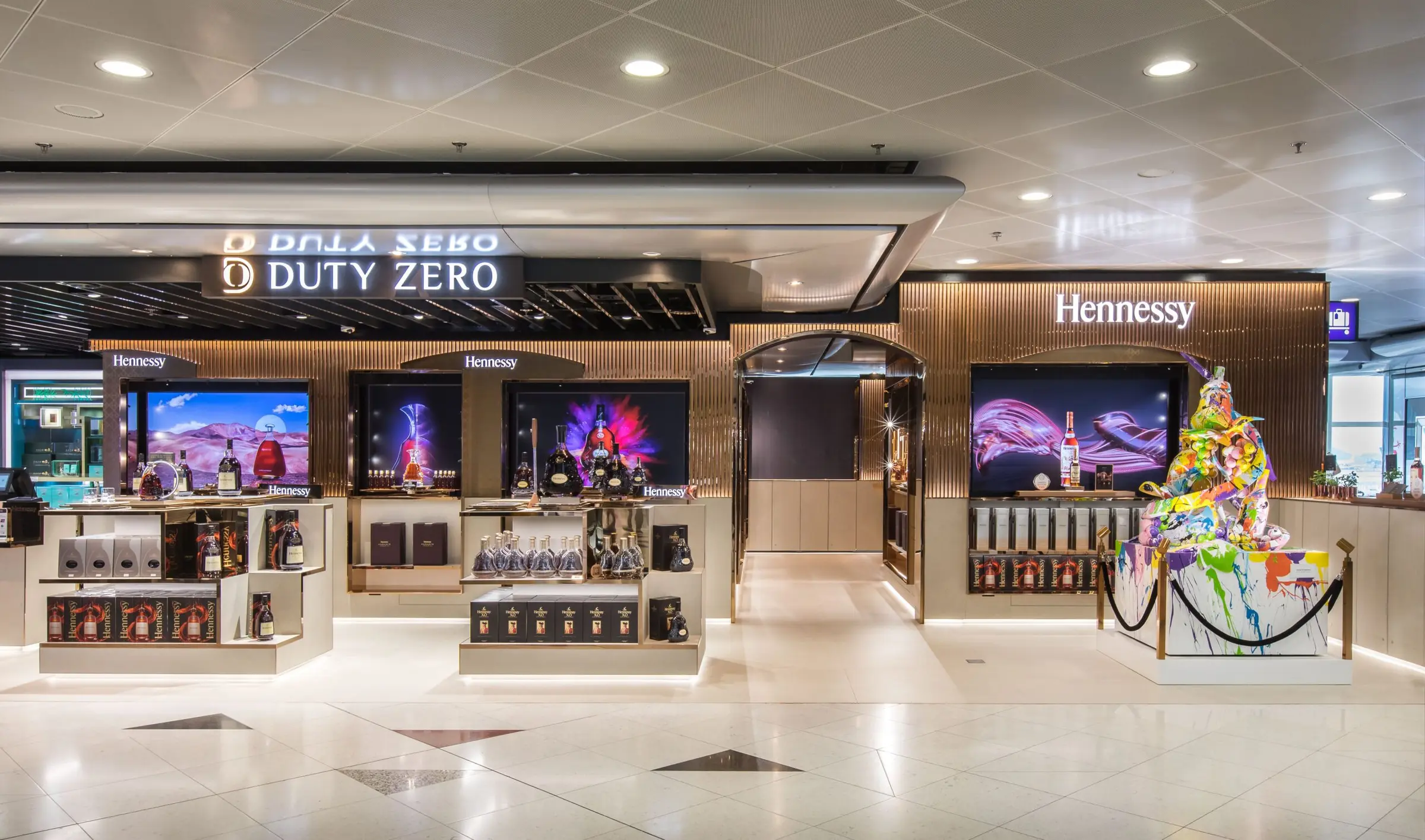 Wide airport storefront with illuminated signage and campaign screen.